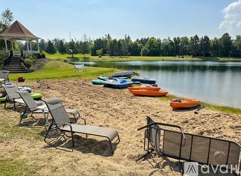 A beach scene with chairs, a gazebo, and boats on the water.