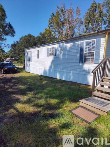 A mobile home with a car parked in front and a wooden deck.