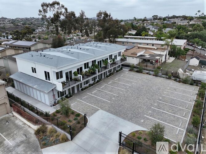 A large white building with a grey roof is surrounded by a parking lot.