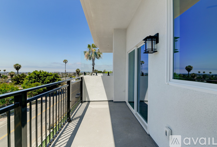 A balcony with a black railing and a view of palm trees.