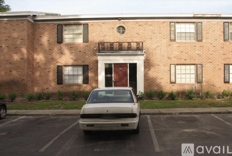 A white car is parked in front of a brick building.