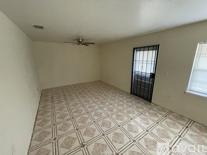 A room with a fan, a window with bars, and a tiled floor.
