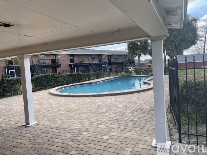 A pool surrounded by a brick patio under a white awning.