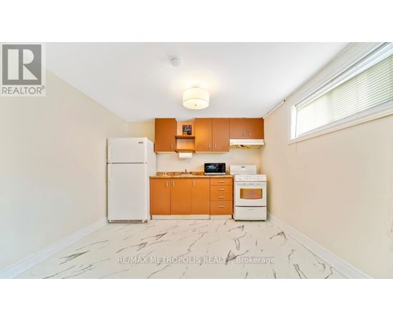A kitchen with a white fridge, orange cabinets, and a marble floor.