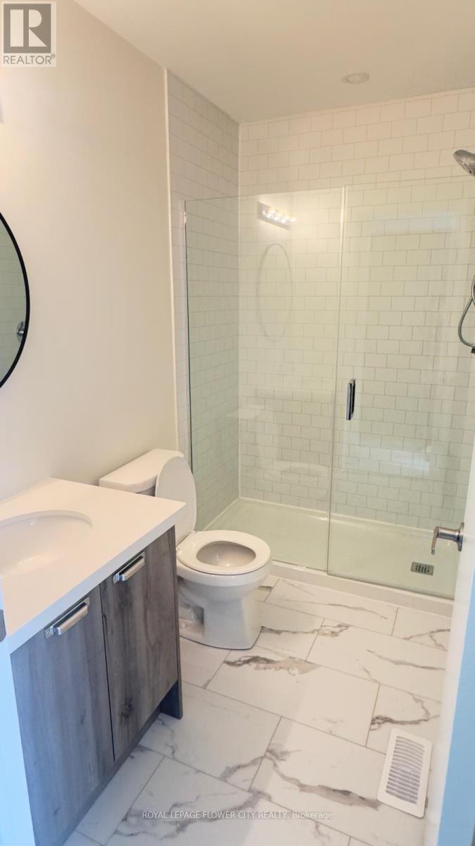 A white toilet sits in a bathroom with a walk-in shower.
