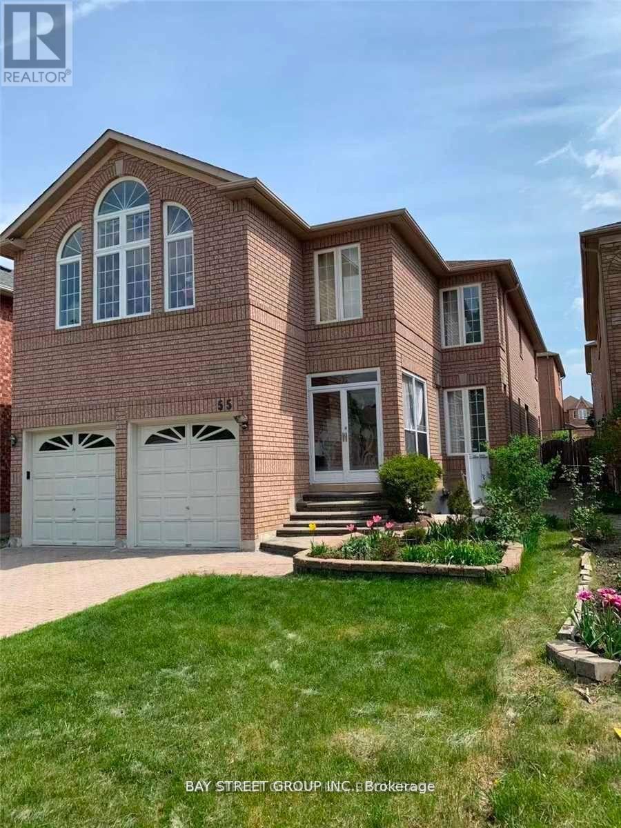 A brick house with a white garage door and a small garden in front.