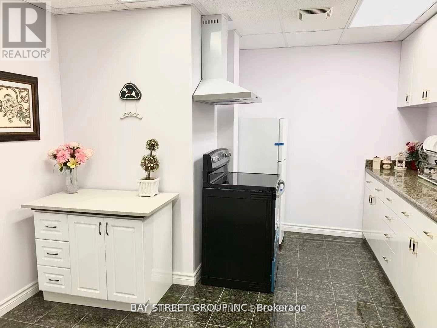 A kitchen with a black fridge and white cabinets.