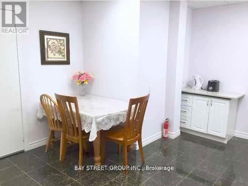 A dining room with a table set for two and a vase of flowers on the table.
