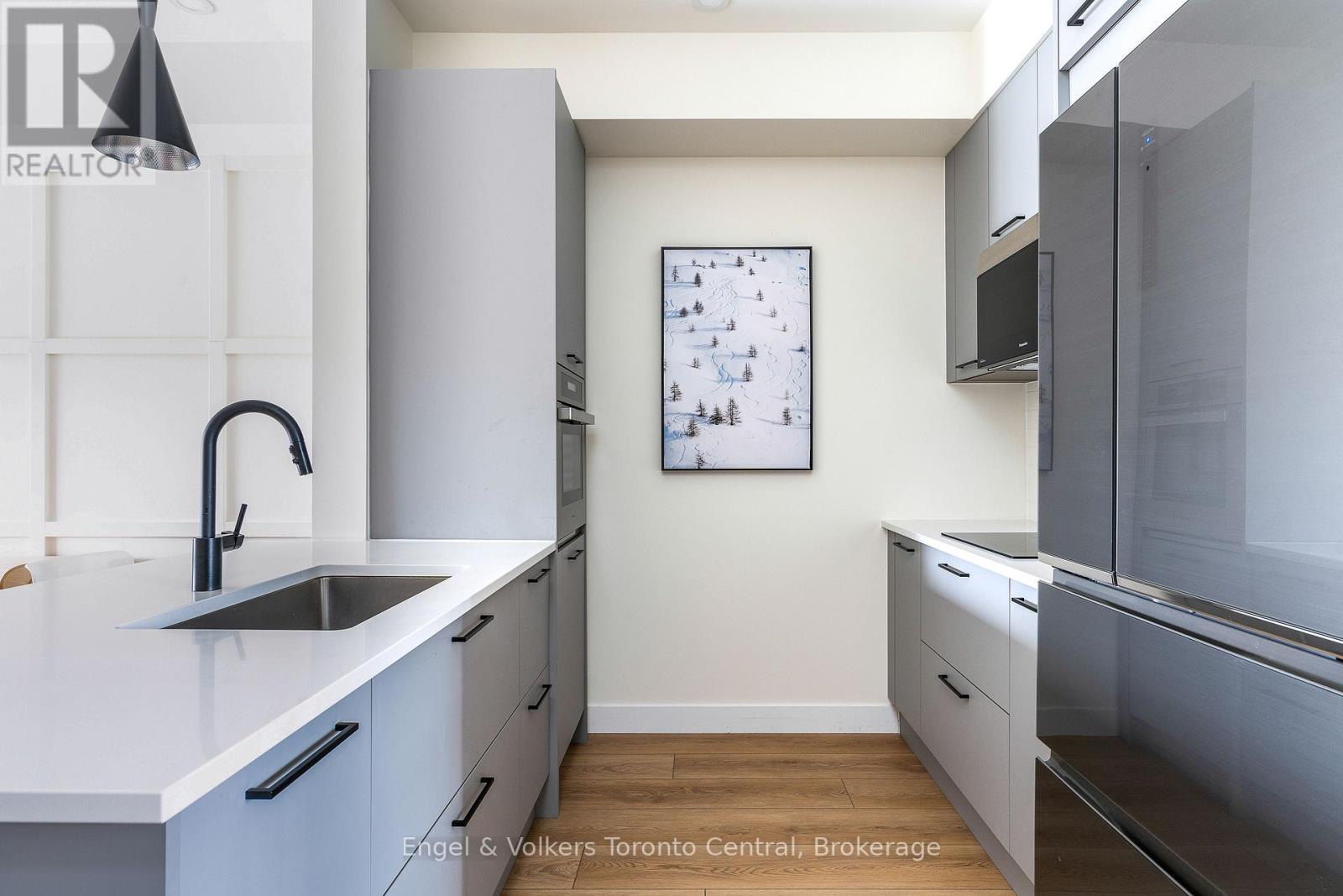 A kitchen with white cabinets and a fridge.