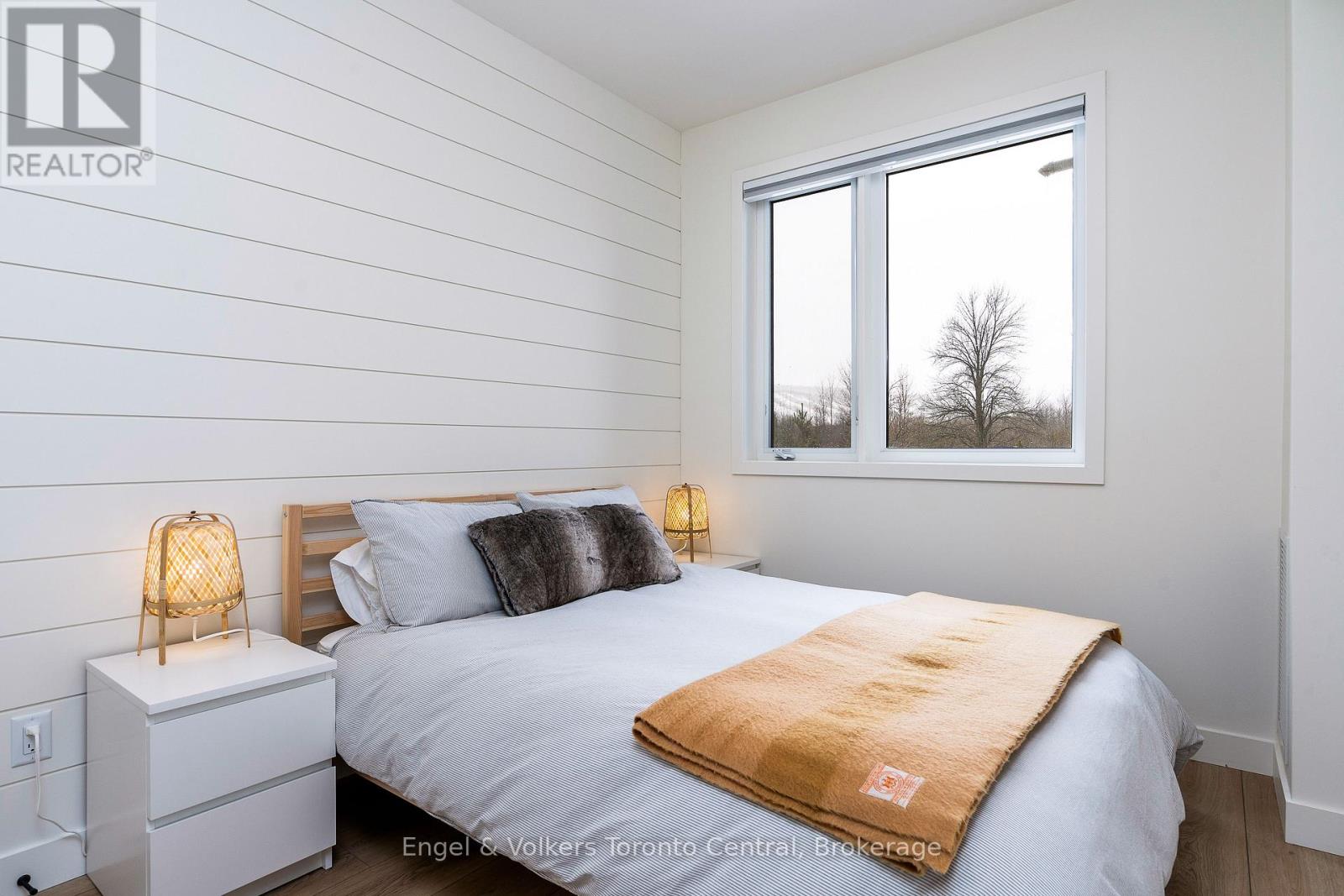 A bedroom with a bed, nightstand, and window.