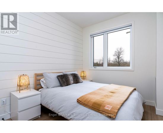 A bedroom with a bed, nightstand, and window.