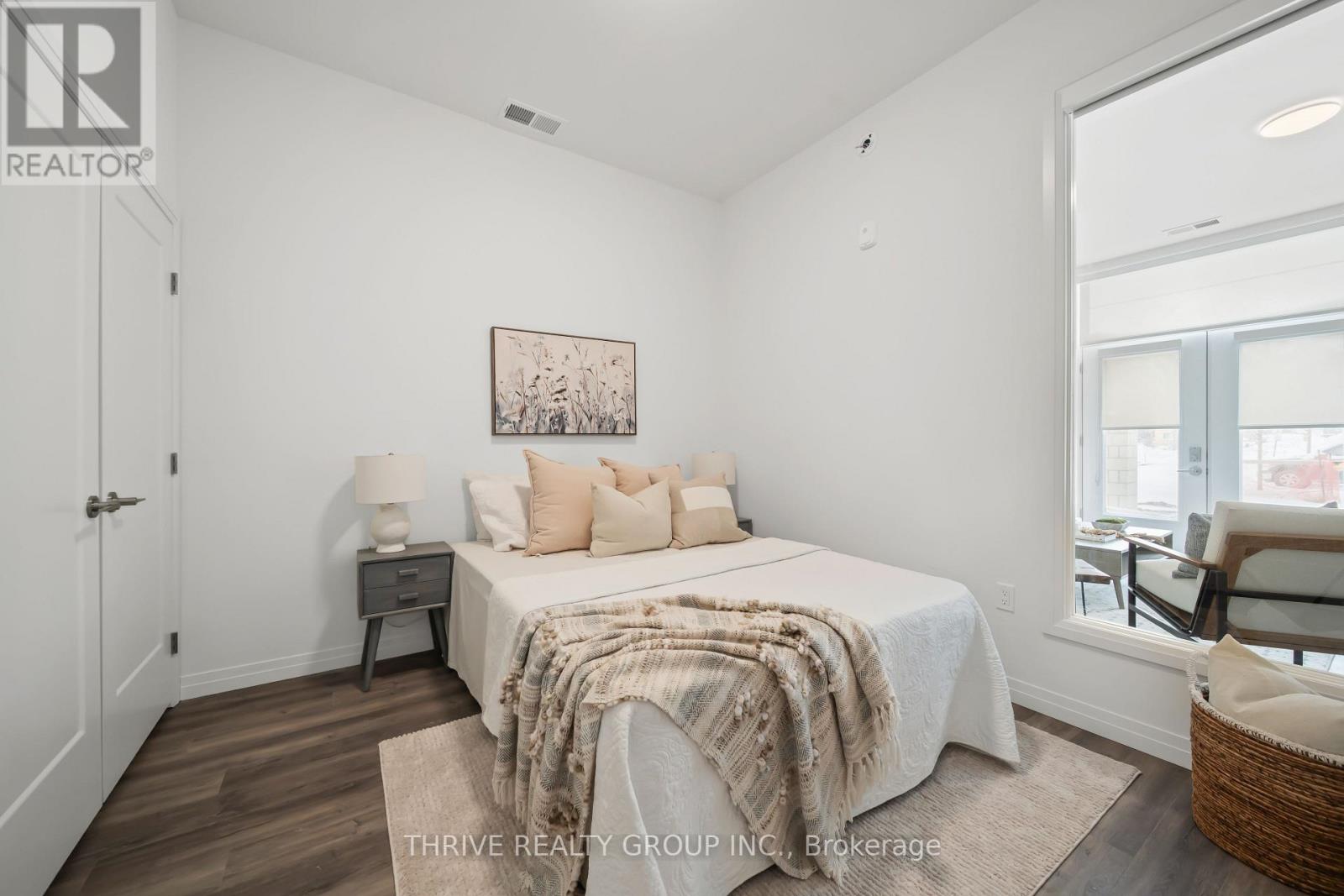 A bedroom with a bed, nightstand, and chair.