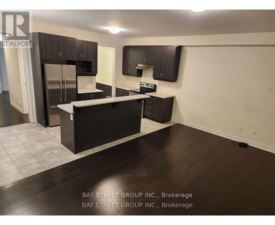 A kitchen with dark wood floors and cabinets, a refrigerator, a sink, and a stove top oven.
