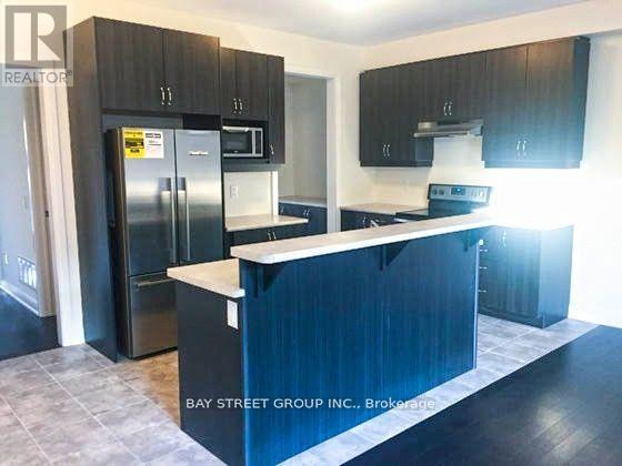 A kitchen with a refrigerator, microwave, and oven.
