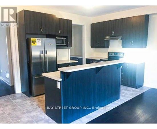 A kitchen with a refrigerator, microwave, and oven.