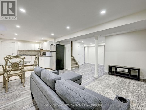A modern living room with a grey sofa and a wooden chair.