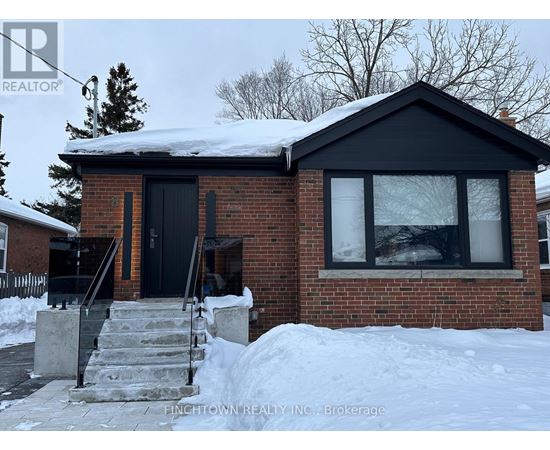 A house with a black door and windows is surrounded by snow.