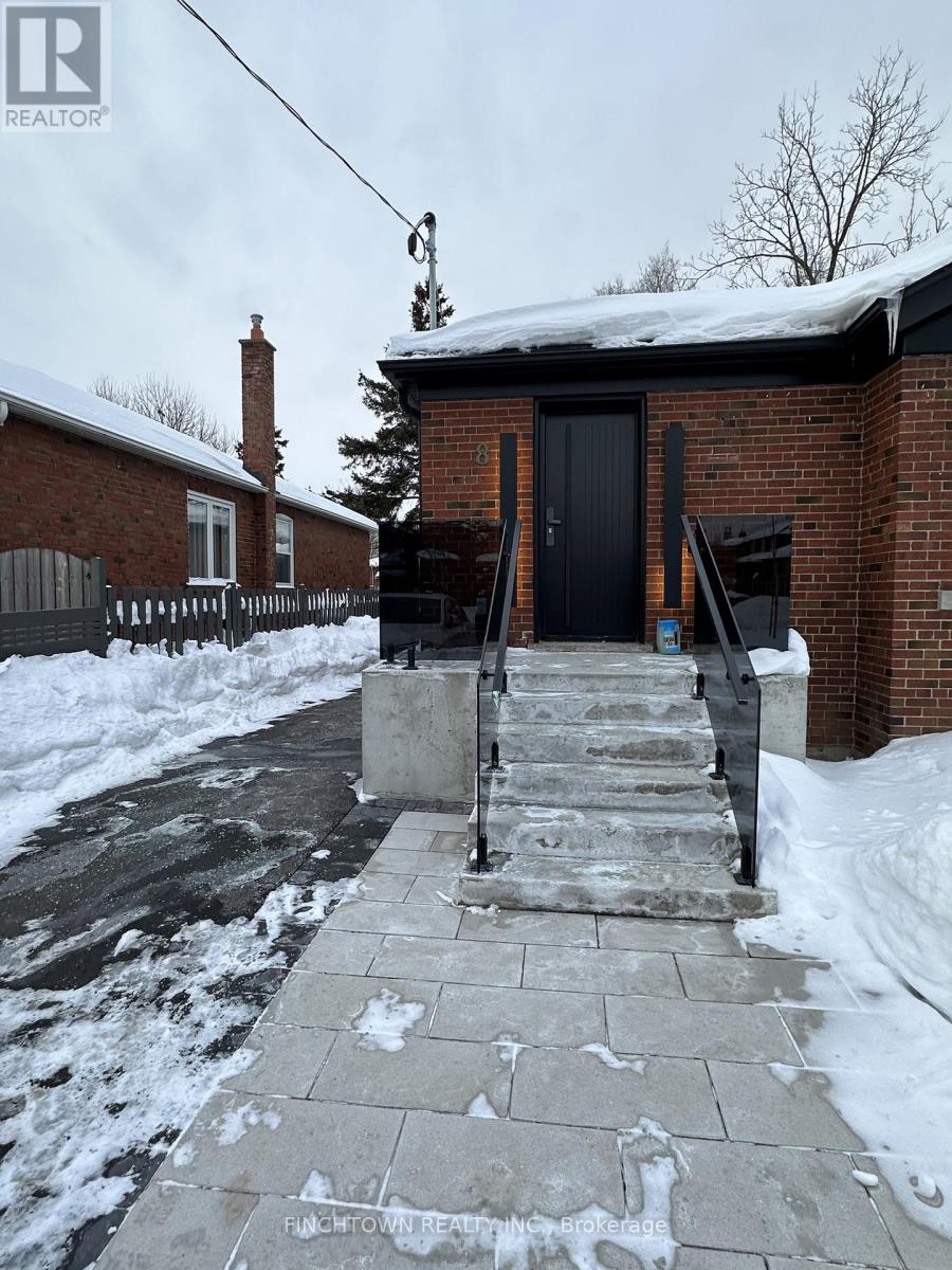 A brick house with a black door and steps leading up to it.
