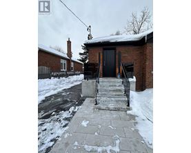 A brick house with a black door and steps leading up to it.