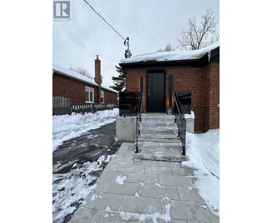 A brick house with a black door and steps leading up to it.