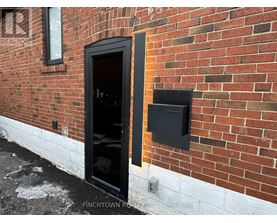 A black door is on the left side of a brick wall.