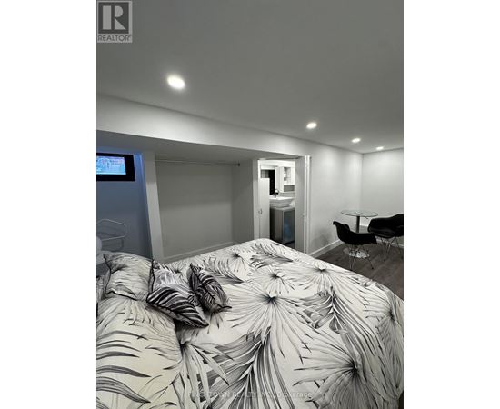 A bedroom with a bed covered in a leaf patterned comforter.