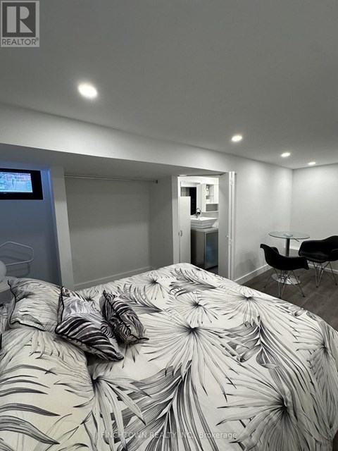 A bedroom with a bed covered in a leaf patterned comforter.
