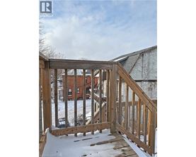 A wooden deck with snow on the ground and a building in the background.