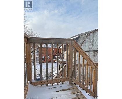 A wooden deck with snow on the ground and a building in the background.