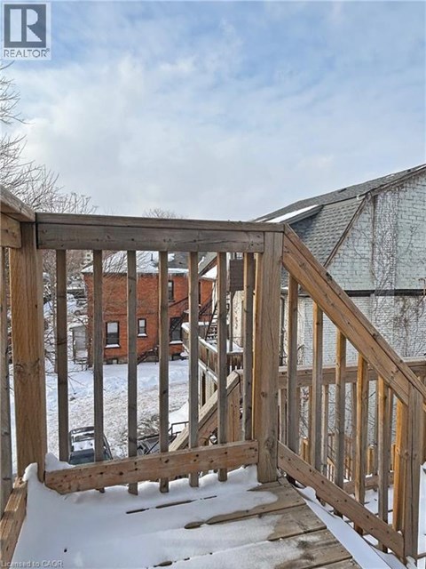 A wooden deck with snow on the ground and a building in the background.