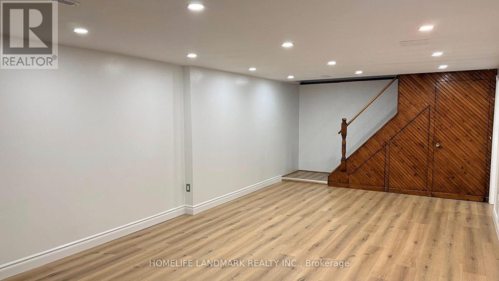 A room with wooden flooring and a staircase on one side.