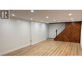 A room with wooden flooring and a staircase on one side.