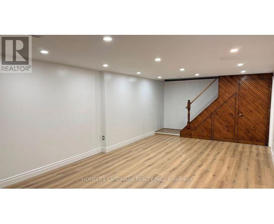 A room with wooden flooring and a staircase on one side.