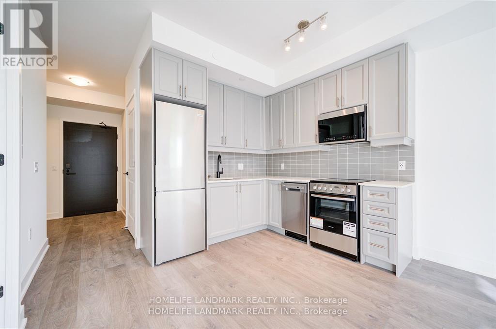 A kitchen with white cabinets and a black refrigerator.