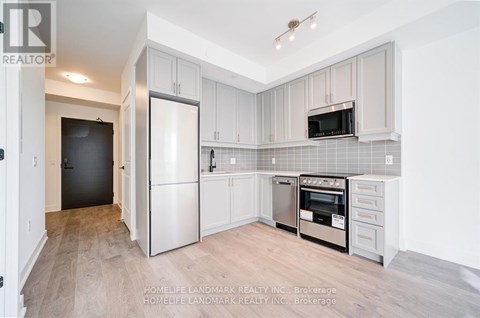 A kitchen with white cabinets and a black refrigerator.