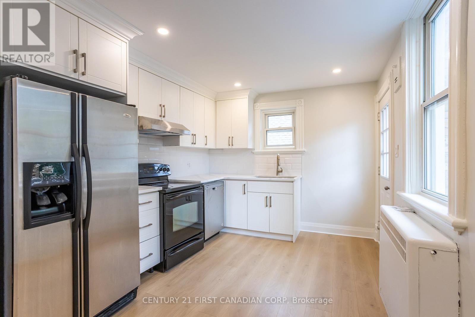 A kitchen with a refrigerator, microwave, oven, and cabinets.