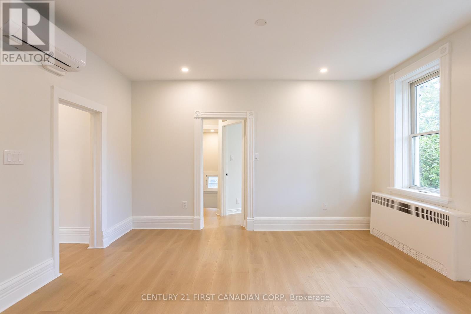 A spacious room with wooden floors and white walls.