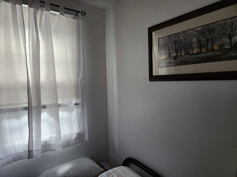 A bedroom with a bed and a painting on the wall.