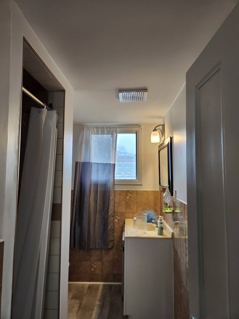 A bathroom with a white sink and a window with curtains.