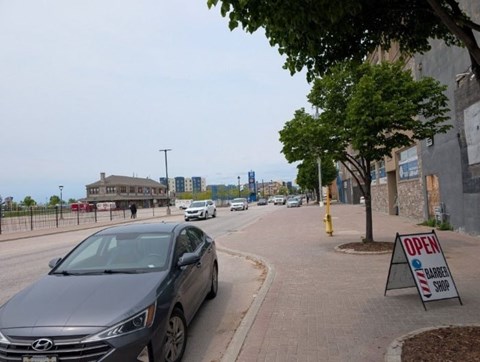 A car is parked on the side of the road next to a sign that says "OPEN".