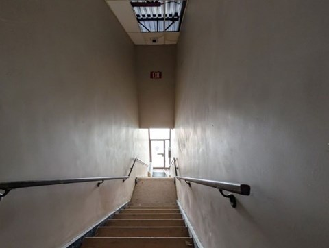 A staircase with a metal railing leads to a door at the end.