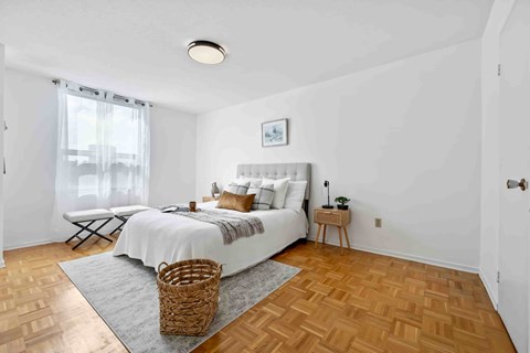A bedroom with a white bed and a wooden floor.