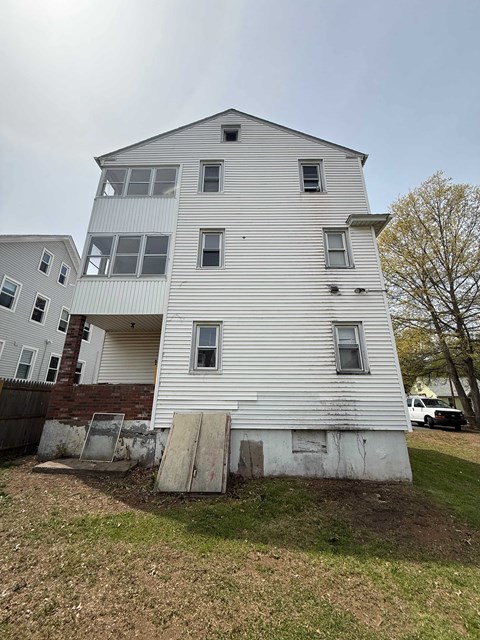 A white two-story building with a boarded-up basement window.