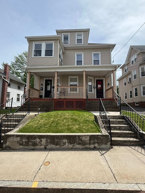 A two-story house with a front porch and a small front yard.