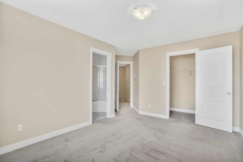 A spacious room with carpeted floor and white doors.
