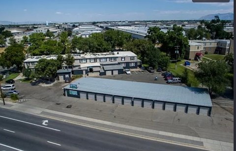 A large building with a blue roof is situated in the middle of a parking lot.