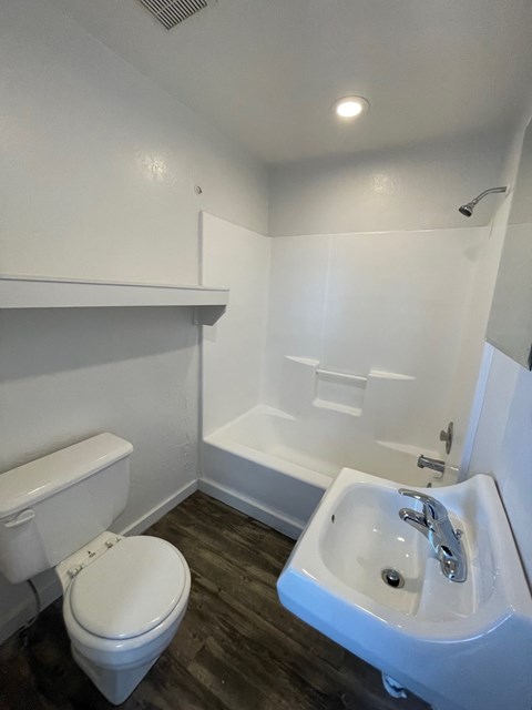 A white toilet sits next to a white sink in a small bathroom.