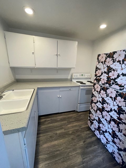 A kitchen with white cabinets and a floral refrigerator.