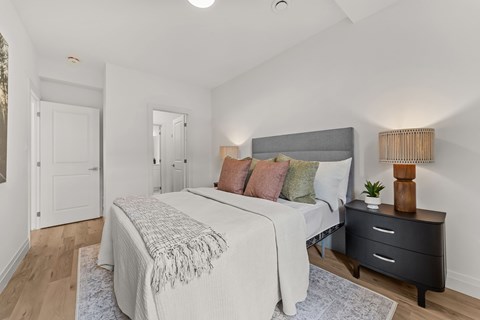 A bedroom with a bed, nightstand, and a lamp.