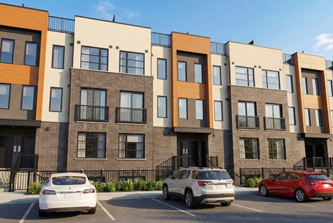 A row of modern apartment buildings with cars parked in front.
